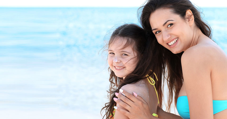 Woman in bathing suit with daughter at beach.